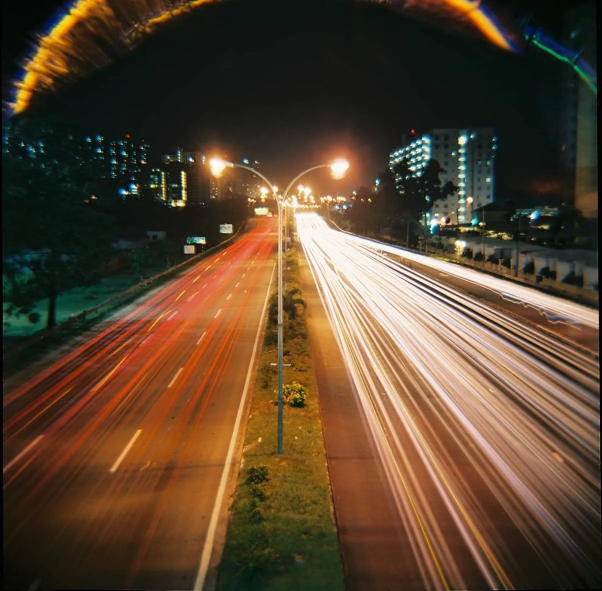 Avenida movimentada à noite com rastros de luz dos veículos